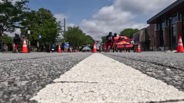 Lawrenceville, GA / USA - 20 Nisan 2024: Ağır çekim, 20 Nisan 2024 'te Lawrenceville, GA' da evsizler için yerel bir bağış toplama etkinliğinde, iki takımın tekerlekli sandalyeler üzerine ev yapımı yatakları ittiğini gösteriyor..