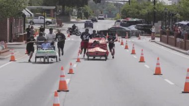 Lawrenceville, GA / USA - 20 Nisan 2024: Telephoto çekimi, 20 Nisan 2024 tarihinde Lawrenceville, GA 'da evsizler için yerel bir bağış toplantısında iki takımın ev yapımı yatakları ittiğini gösteriyor..