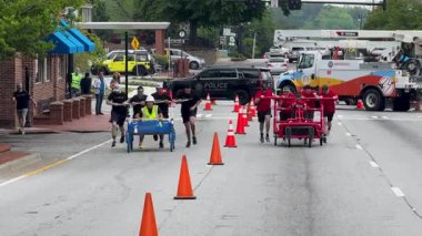 Lawrenceville, GA / USA - 26 Nisan 2025: İki takım, 26 Nisan 2025 'te Lawrenceville, GA' da evsizler için yerel bir bağış toplama etkinliğinde, tekerlek üzerinde ev yapımı yatakları sokağa ittiler..