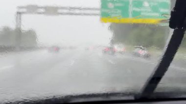 Otomobil cam silecekleri şiddetli bir sağanak nedeniyle hızla yer değiştirirken bir arabanın Atlanta eyaletler arası otobanda ilerlediğini gösteriyor..