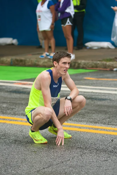 Agotado corredor se arrodilla para recuperar el aliento en Peachtree Road Race —  Fotos de Stock