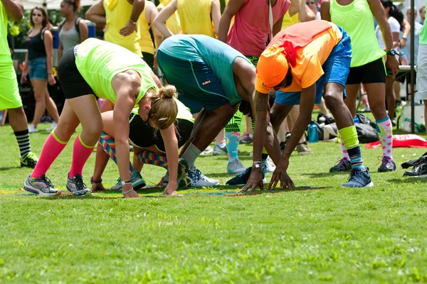 Bend młodych dorosłych i Stretch gry Twister trawy — Zdjęcie stockowe