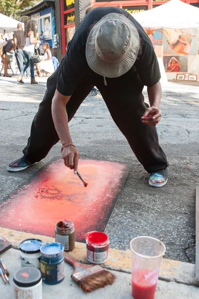 Kunstenaar snelle penbewegingen rode verf op het schilderij op Arts Festival — Stockfoto