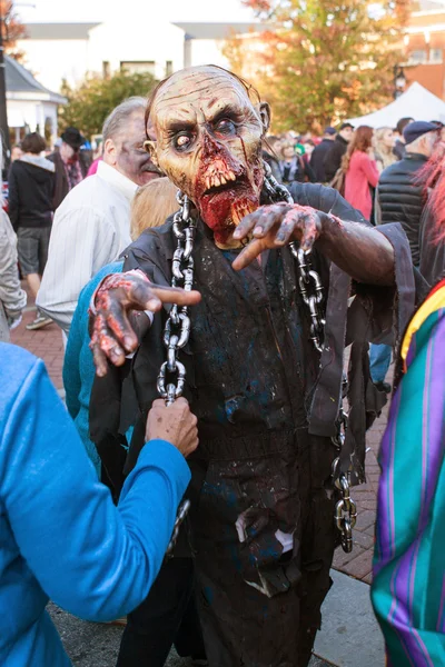 Hombre en espantosa máscara Zombie amenaza a la gente en el Festival de Halloween —  Fotos de Stock