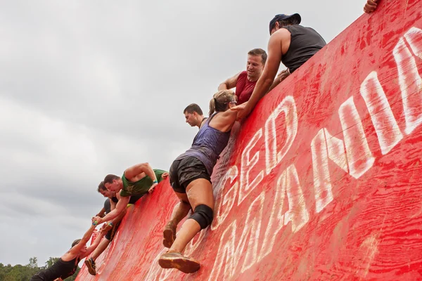 Competidores luchan por escalar la pared en carrera de obstáculos extremos — Foto de Stock