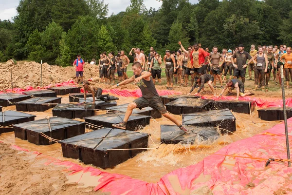 Los competidores corren a través de plataformas flotantes en carrera de obstáculos extremos Imagen de stock