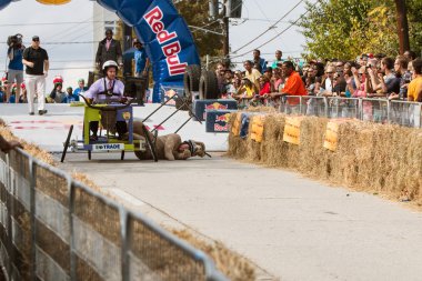 Costumed Competitor Falls Hard From Vehicle In Soap Box Derby clipart