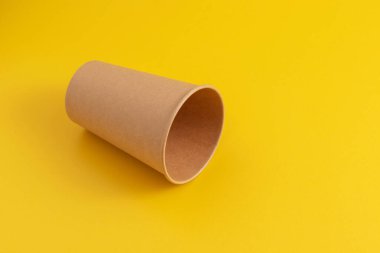 Sarı arka planda boş karton kahve fincanı.