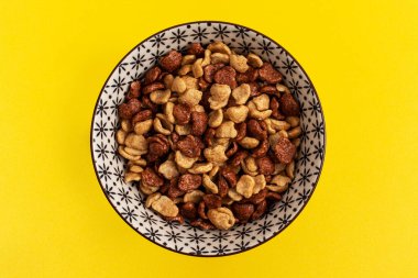 Sarı arka planda bir tabakta açık ve koyu kuru tanelerin karışımı. Üst görünüm.