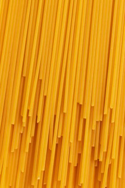 Sarı arka planda pişmemiş kurutulmamış makarna. Üst Manzara. Dikey Tam Çerçeve fotoğrafı.