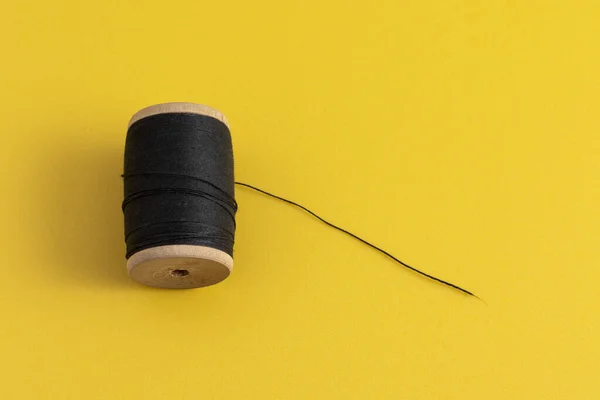 黄色の背景に黒い糸のスプール — ストック写真