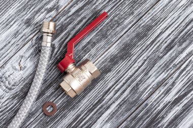 Siyah ahşap masada esnek su hortumu, conta ve top valfi örülmüş..