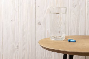 Su bardağı ve ahşap bir masada haplar..