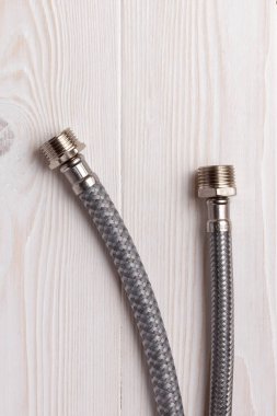 İki tane örülmüş esnek su hortumu. Dış (erkek) lifli esnek hortumlar. Ahşap arka planda.