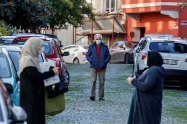 İSTANBUL, Turkey - 5 HAZİRAN 2021. Yüz maskeli bir adam sokakta yürüyor. Ön planda odak dışı, iki kadın konuşuyor..