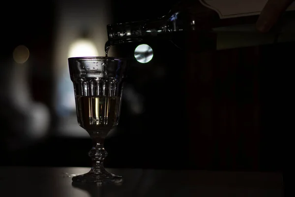 手は暗い部屋のガラスにワインを注ぐ アルコール依存症の概念 焦点を絞った写真 — ストック写真