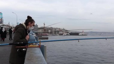 İSTANBUL, Turkey - 5 HAZİRAN 2021. Galata Köprüsü. Balıkçı elinde oltayla Boğaz 'da balık yakalar..