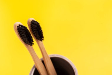 İki ahşap diş fırçası. Plastiksiz, kişisel ağız temizliği için çevre dostu ekipmanlar. Sarı arkaplan.