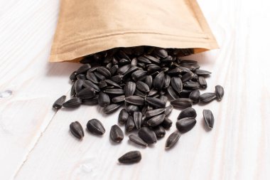 Mikro yeşillik yetiştirmek için ayçiçeği tohumlarıyla dolu kağıt torba. Beyaz ahşap bir arka planda. Kapat..