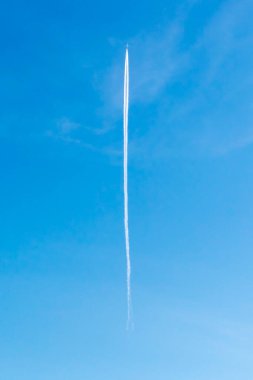 Yoğunlaşma izi olan mavi gökyüzünde uçan bir uçak. Gökyüzündeki uçaktan iz sür.