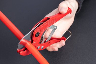 Adam plastik boruyu manuel boru makasıyla keser..