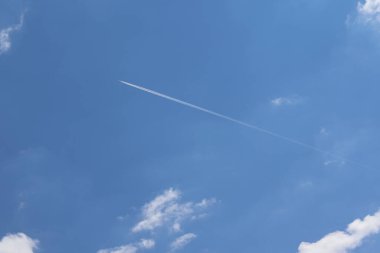 Mavi gökyüzünde zıtlaşan bir jet. Uçak buğulanma izi ile uçar.