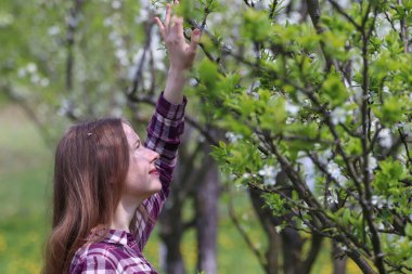 Çiçekli erik bahçesindeki bir kadının açık hava portresi..