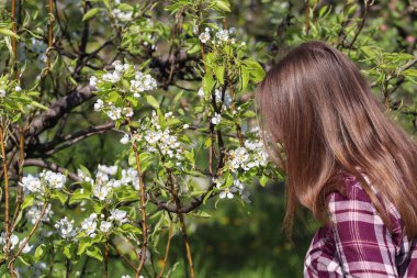 Bahçedeki çiçek açan armut ağacının yanındaki bir kadının açık hava portresi..