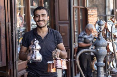 Gaziantep, Türkiye - 3 Eylül 2021. El sanatları ustası el yapımı bakır çaydanlıklar ve çakmaktaşlar gösteriyor..
