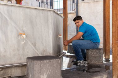 Gaziantep, Türkiye - 4 Eylül 2021. Bir çay satıcısı caminin yanında bardak yıkıyor..