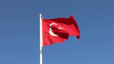 Mavi gökyüzünün arka planında Türkiye bayrağı sallıyor.