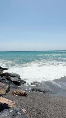 ALMUNECAR, SPAIN - 28 AĞUSTOS 2025: İspanya 'nın Almunecar kentindeki fırtınalı turkuaz dalgalar altında dramatik gökyüzü ve güçlü sörfler altında dinlenmek.