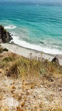 İspanya 'nın Herradura yakınlarındaki denizin turkuaz dalgaları, parlak güneş ışığı altında yavaşça kıyıya doğru yuvarlanıyor..