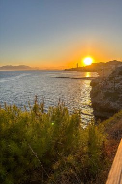 Sunset over the sea in Rincn de la Victoria, Malaga, Spain, with golden light reflecting on calm waves along the coast.