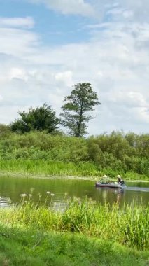 ONISHKI, UKRAINE - 12 Temmuz 2025: Ukrayna 'nın Poltava bölgesindeki Sula Nehri' nin sakin suları boyunca küçük bir teknede sürüklenen balıkçılar.