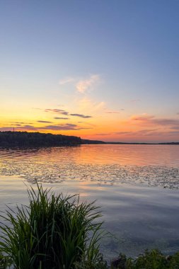 Günbatımında huzurlu bir yürüyüş Ternopil, Ukrayna 'daki Ternopil Gölü boyunca devam ediyor. Sakin sular ve bereketli çevre sakin bir kent inzivası yaratıyor..