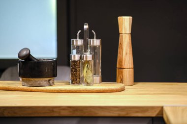 Havan topu ve karabiber karıştırıcı ve değirmen masada. Karanlık arka planda modern tarzda yemek pişirmek için mutfak gereçleri. Ev dekorasyonu. Modern ev dekorasyonu