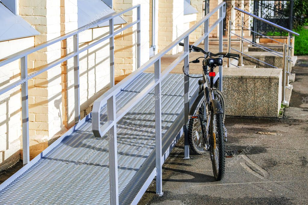 A ramp for wheelchairs. The bike is in the foreground, attached to the railing with an anti-theft cable and locked