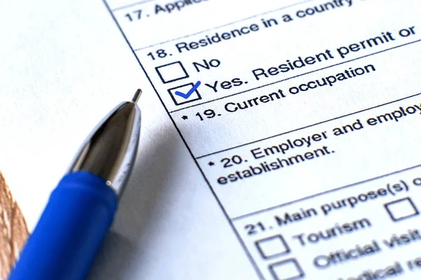 Application form for a Schengen visa. The form and pen are on the table