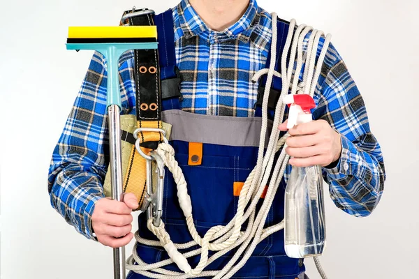 Safety belt on the employees shoulders. Cleaning supplies in the hands of a cleaning company employee. Cleaning services with professional equipment. — Stock Photo, Image