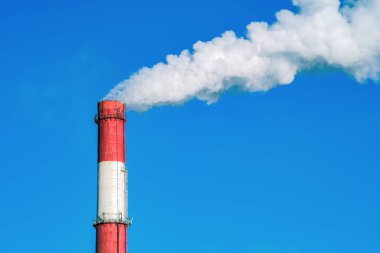 Mavi gökyüzü arka planında endüstriyel boru. Gökyüzüne duman bulutları fırlatır. Dioksit yüzünden hava kirliliği. Çevre kirliliği.