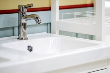 Yeni seramik lavabo ve modern krom musluk şık bir mutfak içinde..