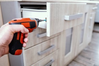 Mutfak mobilyalarını klasik tarzda monte eden usta vidayı elektrikli tornavidayla çeviriyor. El işi kavramı..