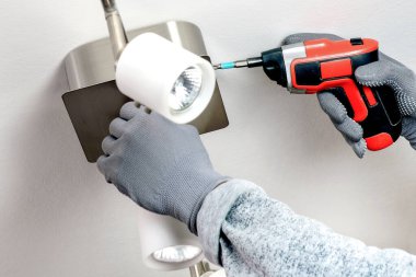 Usta bir elektrikçi halojen lambalarla bir çorap yerleştirir. Tamir ve bakım kavramı