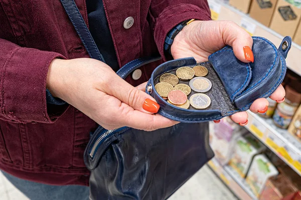 Eine Frau hält eine Handtasche mit mehreren Münzen in der Hand. Nach dem Bezahlen im Geschäft, Check-in Hand. — Stockfoto