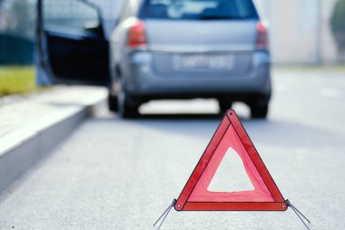 Arka planda kırık arabalı acil durum dur işareti.