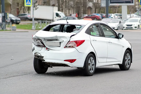 Kollision mellan bilar. Den vita taxibilen fick allvarliga skador på den bakre delen av karossen. Krossad stötfångare och baklucka. — Stockfoto