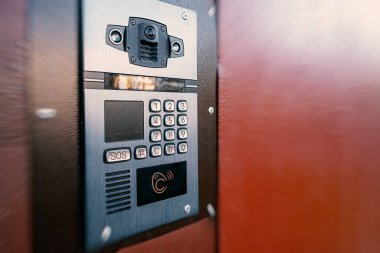 Eve gelen aramaları kaydetme yeteneğine sahip dijital dahili telefon. Kodu girmek için düğmeler ve manyetik okuyucu. Evin önünde dahili telefon var..