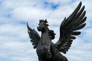 Kanatlı bir pegasus atının bronz heykeli. Bulutlu mavi gökyüzü arkaplanı. Saint-Petersburg 'da. - Rusya. 2 Haziran 2021