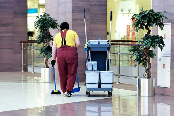 Temizlikçi çöpü süpürür. Alışveriş merkezinin ıslak temizliği için evrensel bir set. Modern bir temizlik şirketi, tekerlekli bir tramvayda temizlik seti, her amaç için mükemmel bir tasarım..